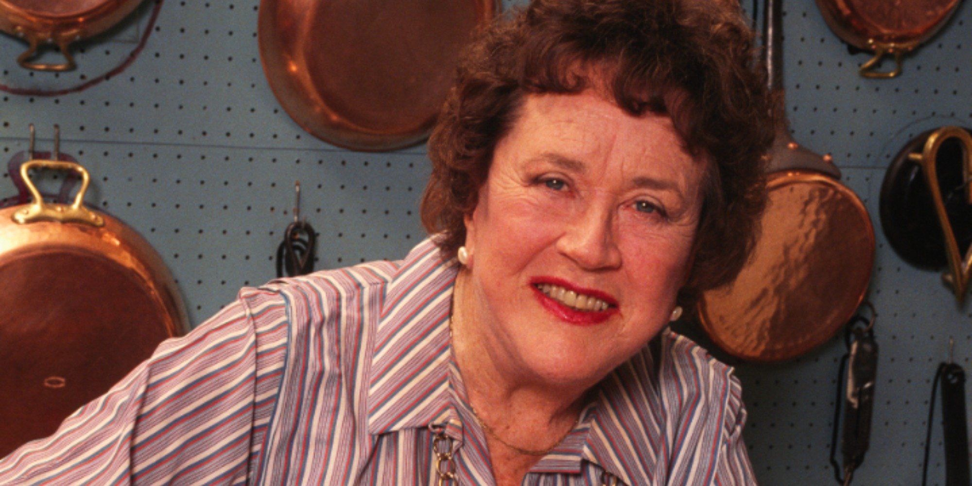 Julia Child poses for a photograph in her home kitchen.