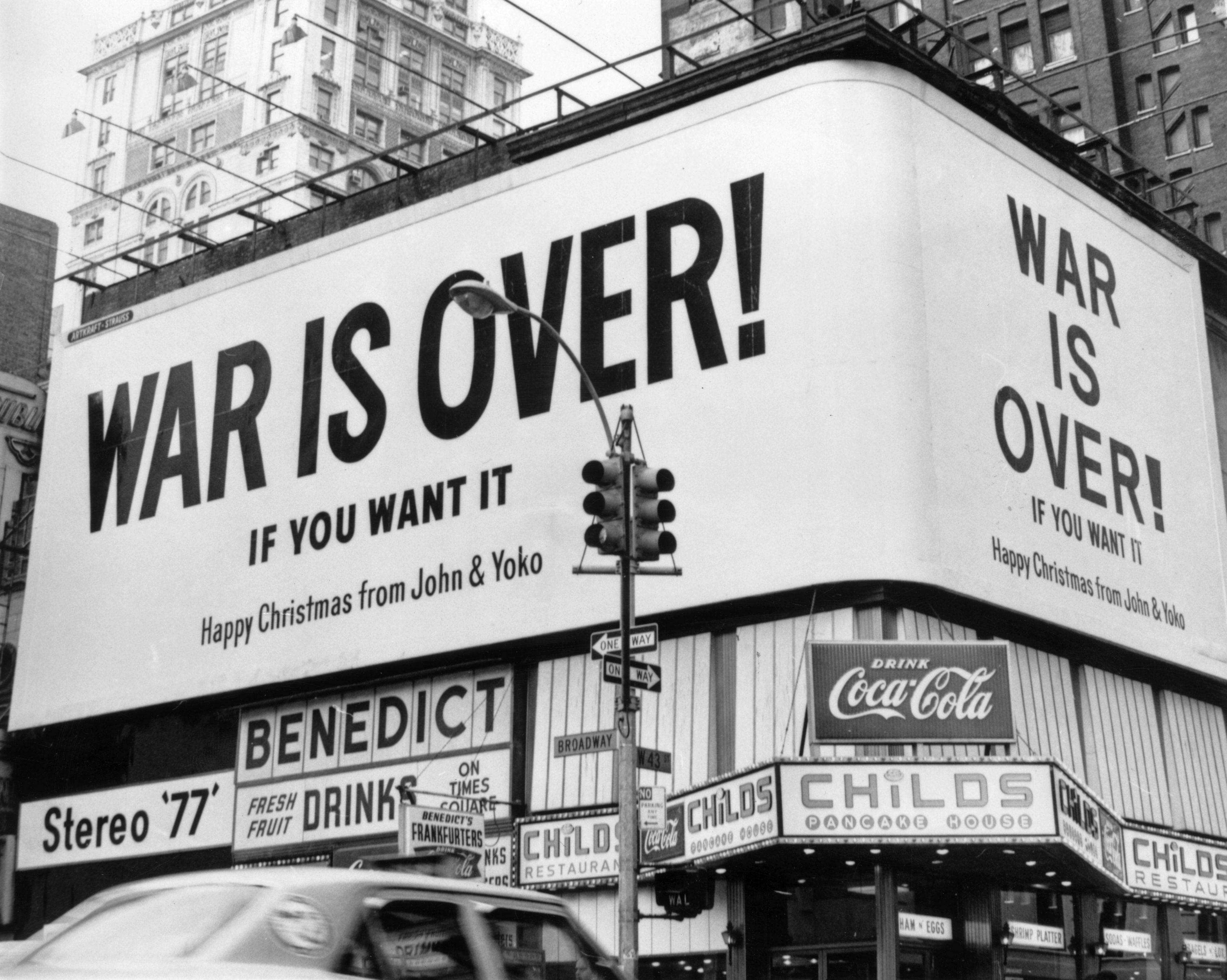 One of John Lennon and Yoko Ono's billboards reading "War Is Over" near a Coca-Cola advertisement