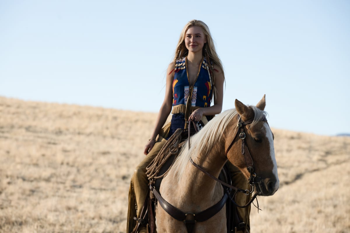 Isabel May as Elsa in the Taylor Sheridan series 1883. Elsa rides Lightening wearing the vest Sam gave her and smiling. 