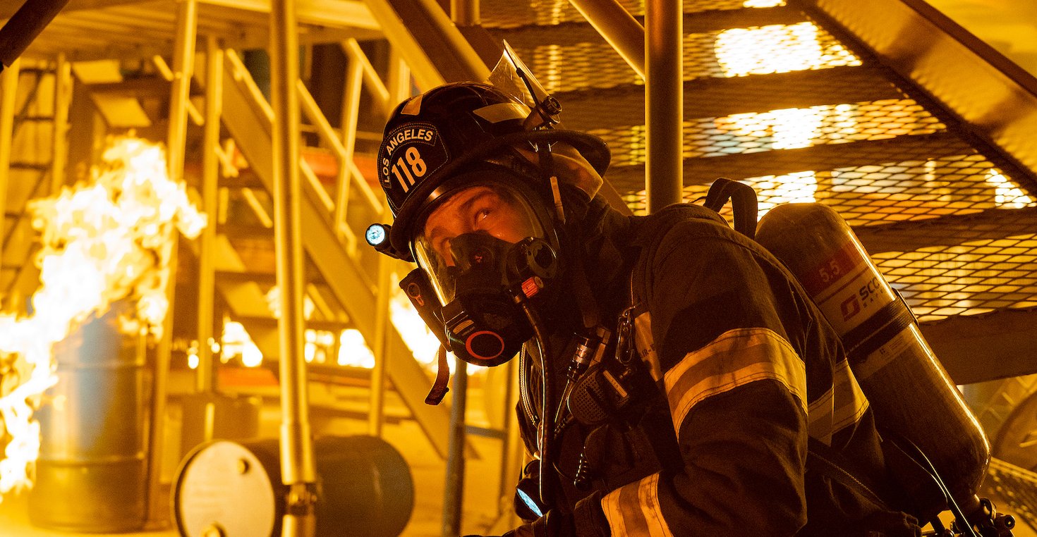 '9-1-1' Season 5 cast member Oliver Stark as Buck wearing head-to-toe firefighting gear while in a burning building