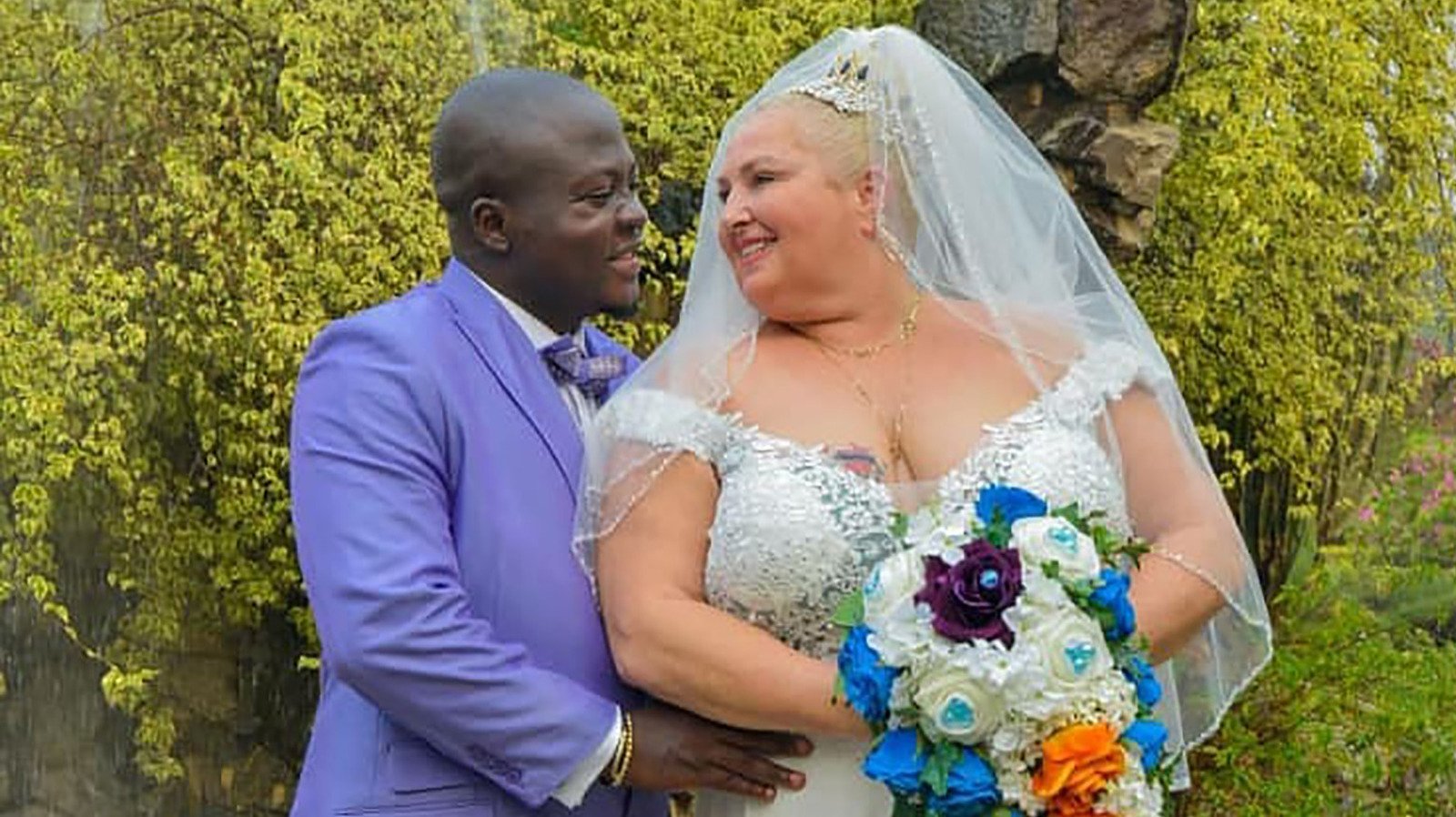 Michael Ilesanmi in a blue tuxedo and Angela Deem wearing a white wedding dress during their wedding on '90 Day Fiancé'.