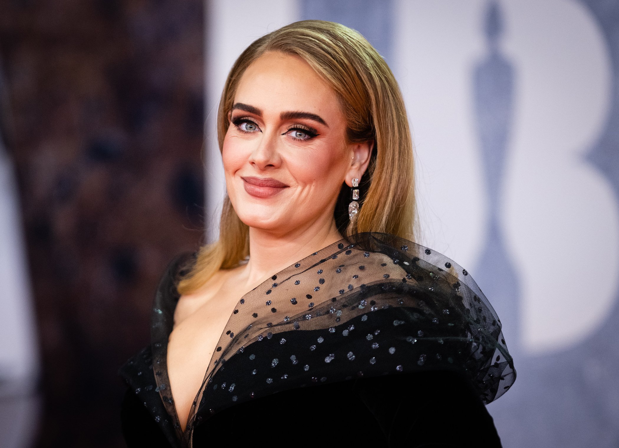 Adele in a black dress smiling at the camera at an awards ceremony