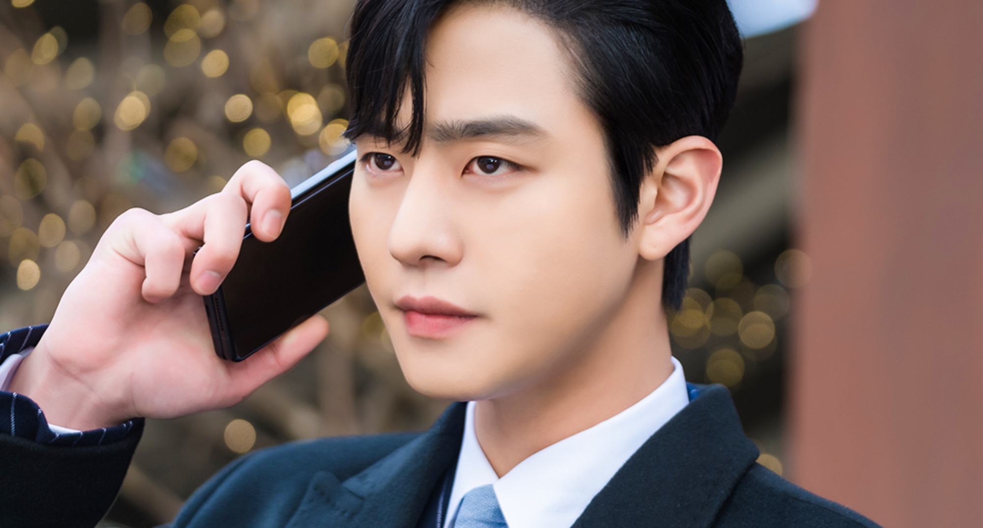 Ahn Hyo-seop as Tae-mu in 'Business Proposal' using a cellphone and wearing suit.