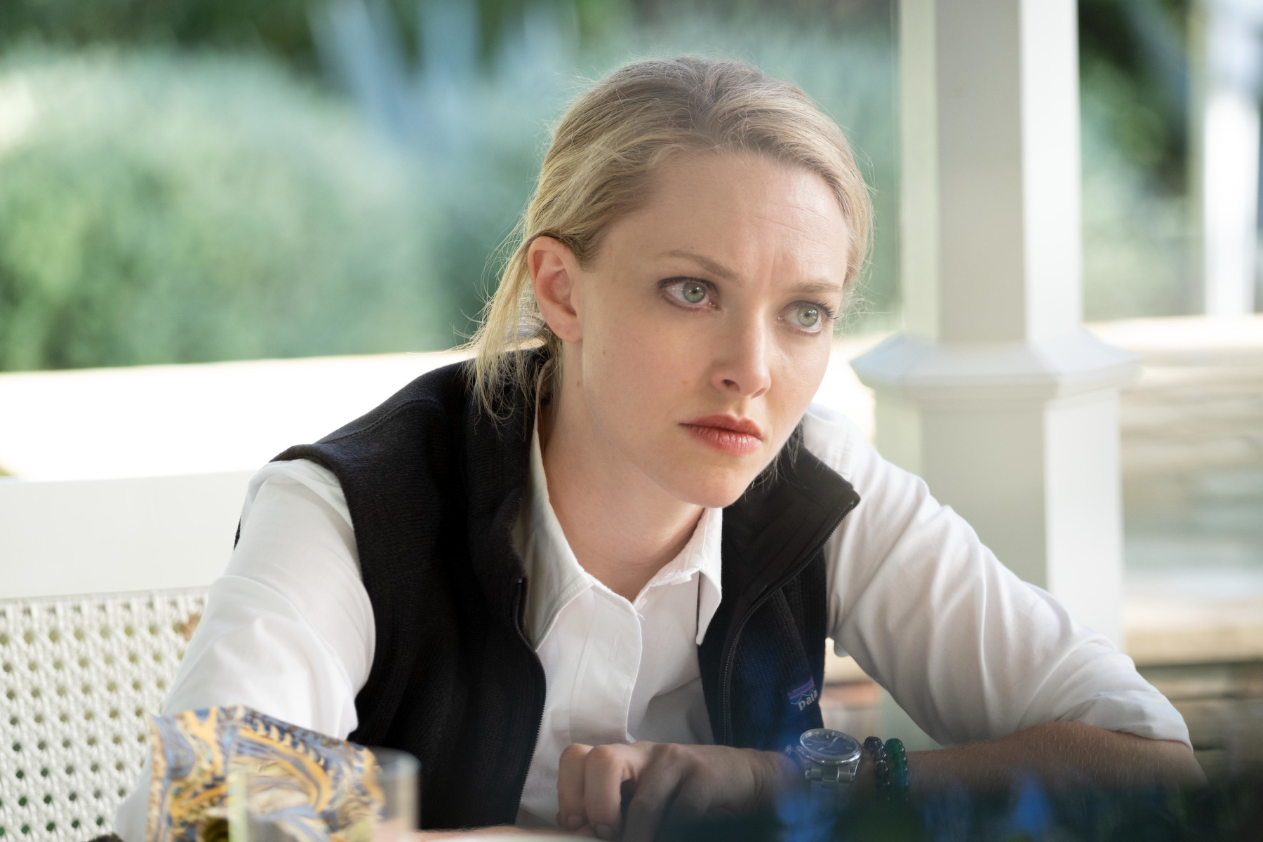 Amanda Seyfried in 'The Dropout' Episode 6 on Hulu. She's sitting at a table and leaning forward.
