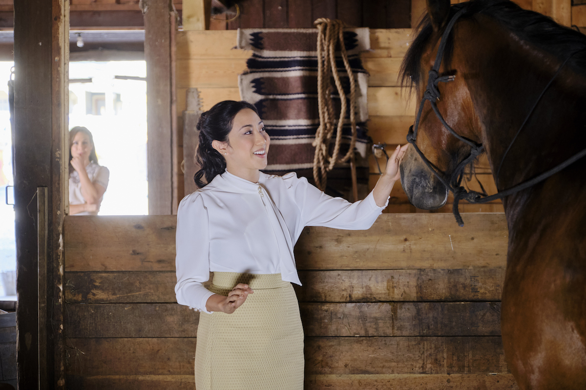 Amanda Wong as Mei Sou, touching a horse, with Elizabeth in the background in an episode of 'When Calls the Heart' Season 9
