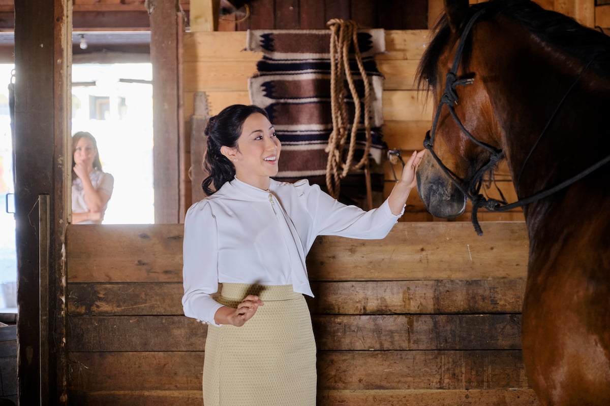 Amanda Wong as Mei Sou, touching a horse, with Elizabeth in the background in an episode of 'When Calls the Heart' Season 9