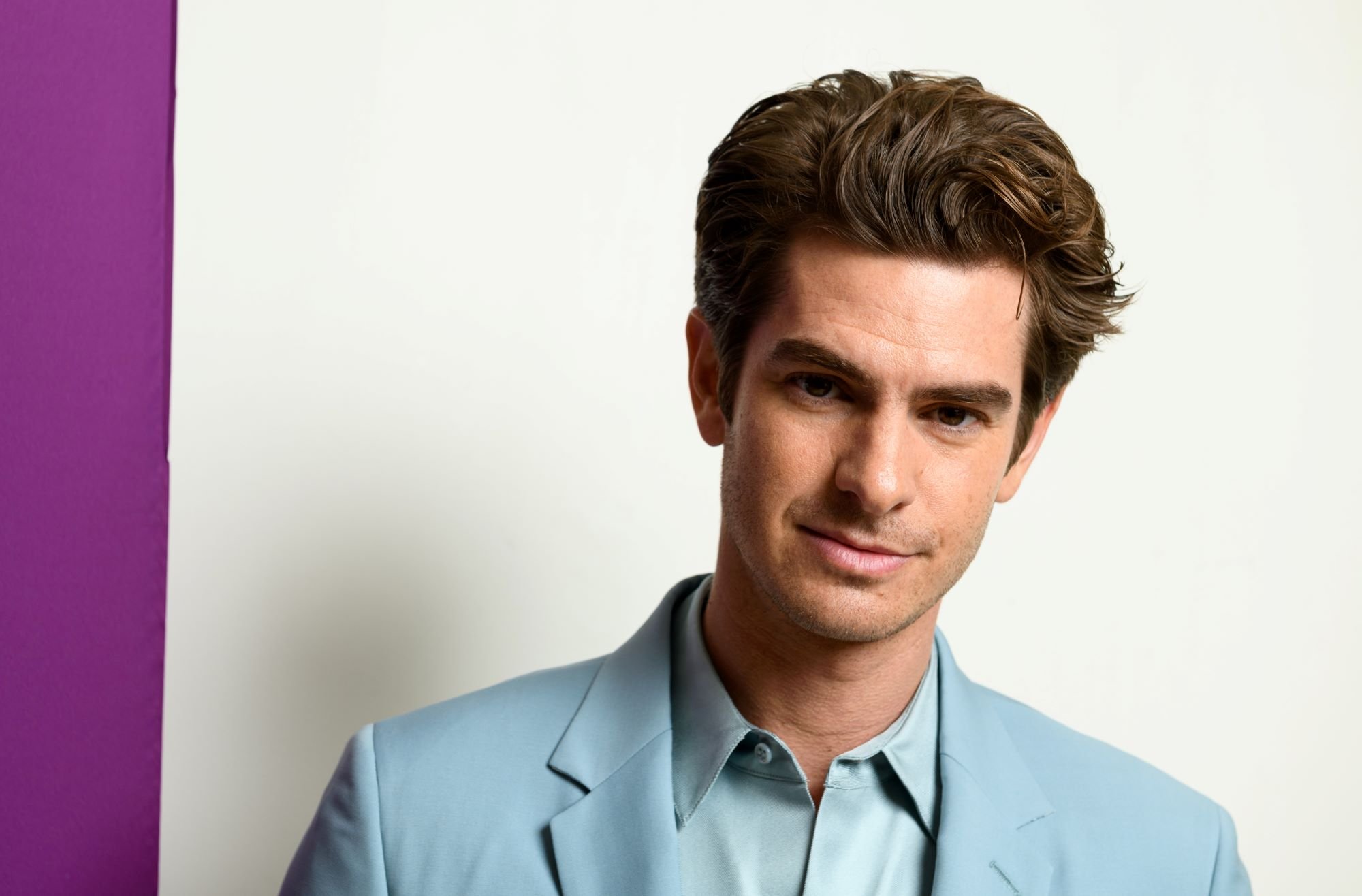 Andrew Garfield, a part of the 'Spider-Man: No Way Home' cast, wears a light blue suit over a light blue button-up shirt.