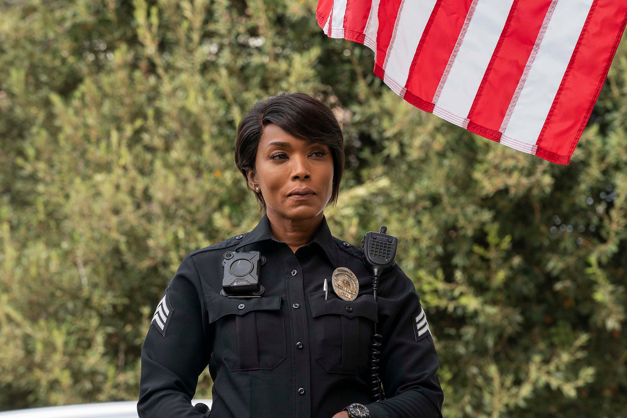 Athena Grant, played by Angela Bassett, standing in uniform on '9-1-1' behind an American flag.