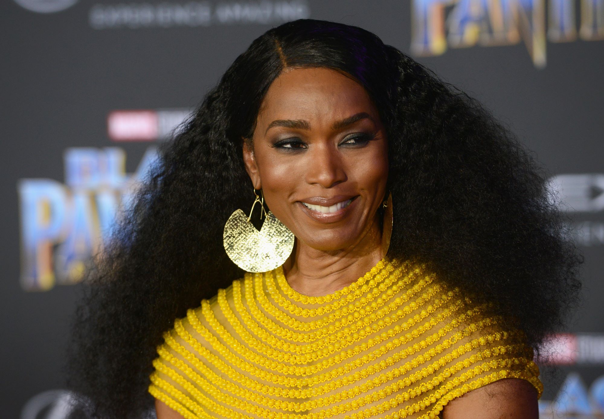 'Black Panther 2' star Angela Bassett wears a yellow short-sleeved dress and big circle gold earrings.