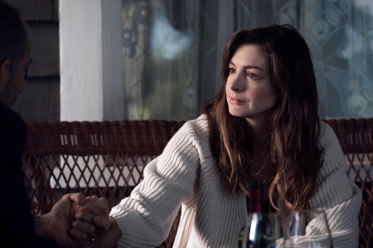 Anne Hathaway wears a white sweater and looks on in 'WeCrashed' Season 1 Episode 3: 'Summer Camp'