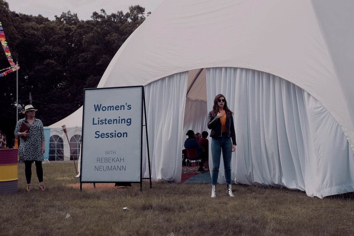 Anne Hathaway stands outside a white tent in 'WeCrashed' Season 1 Episode 3: 'Summer Camp'