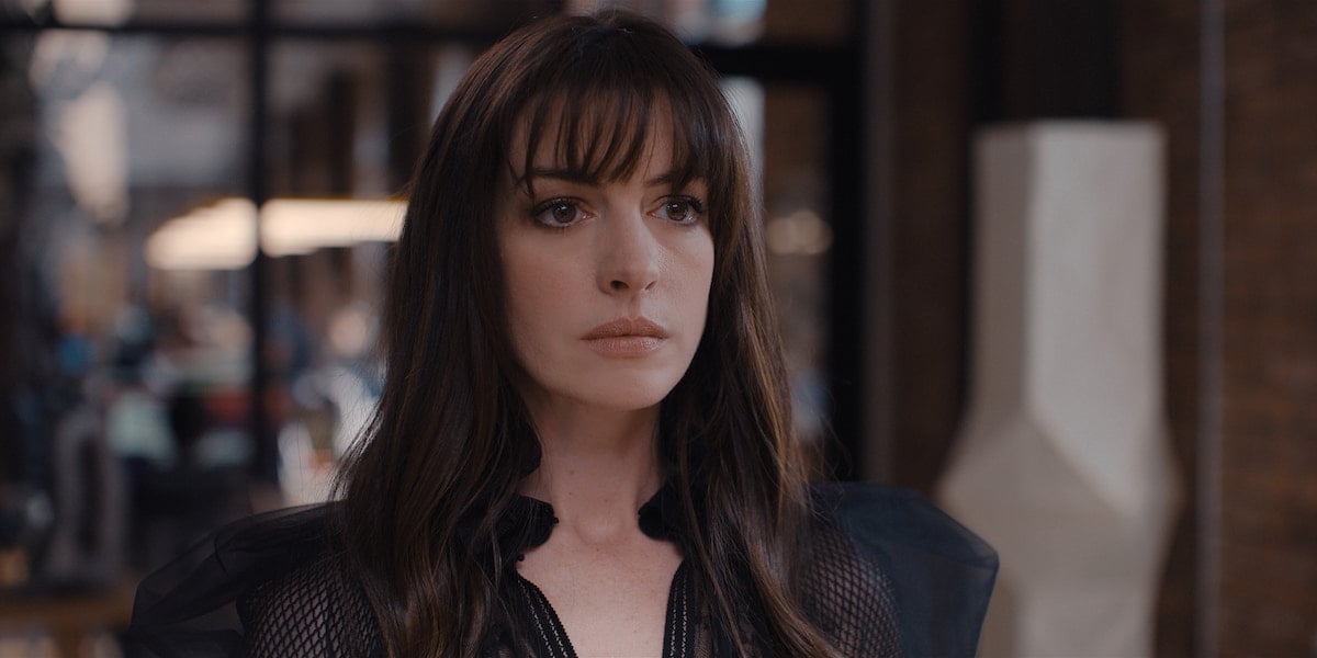 Anne Hathaway looks on wearing a black shirt in a scene from 'WeCrashed' Season 1 Episode 5: 'Hustle Harder'