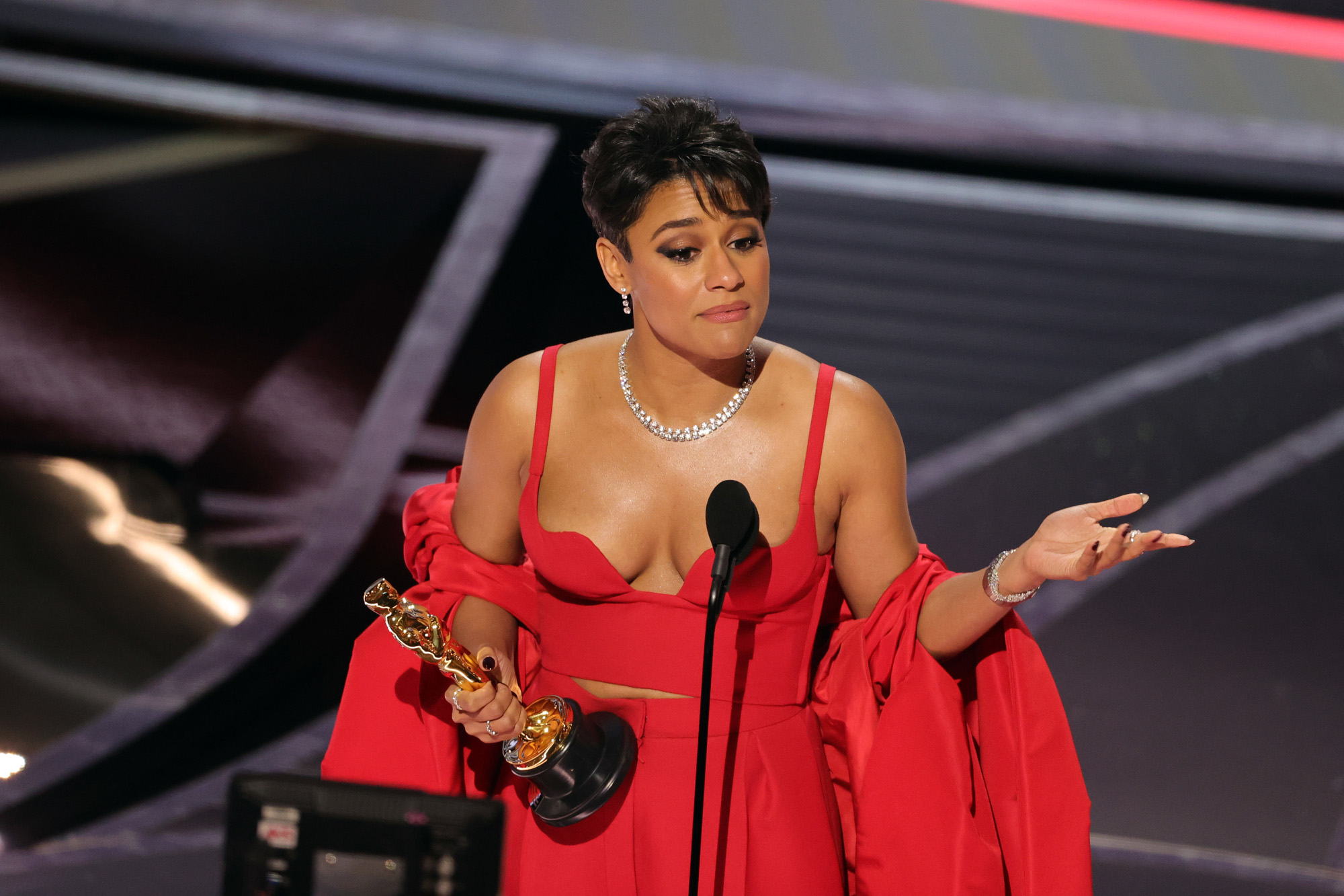 'West Side Story' star Ariana DeBose wins Best Supporting Actress at the 2022 Oscars. She's wearing a red dress and holding the trophy.