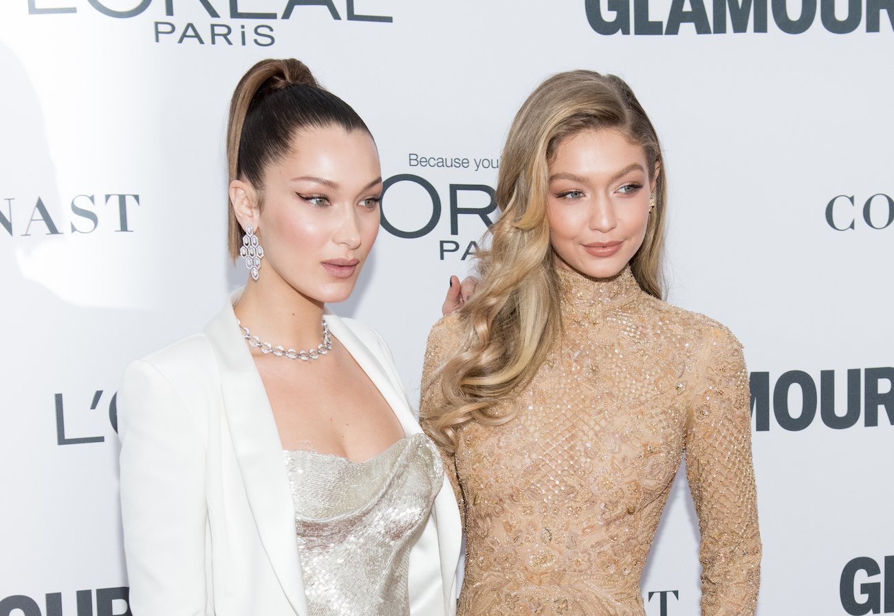 Bella Hadid and Gigi Hadid posing next to each other in front of a white background