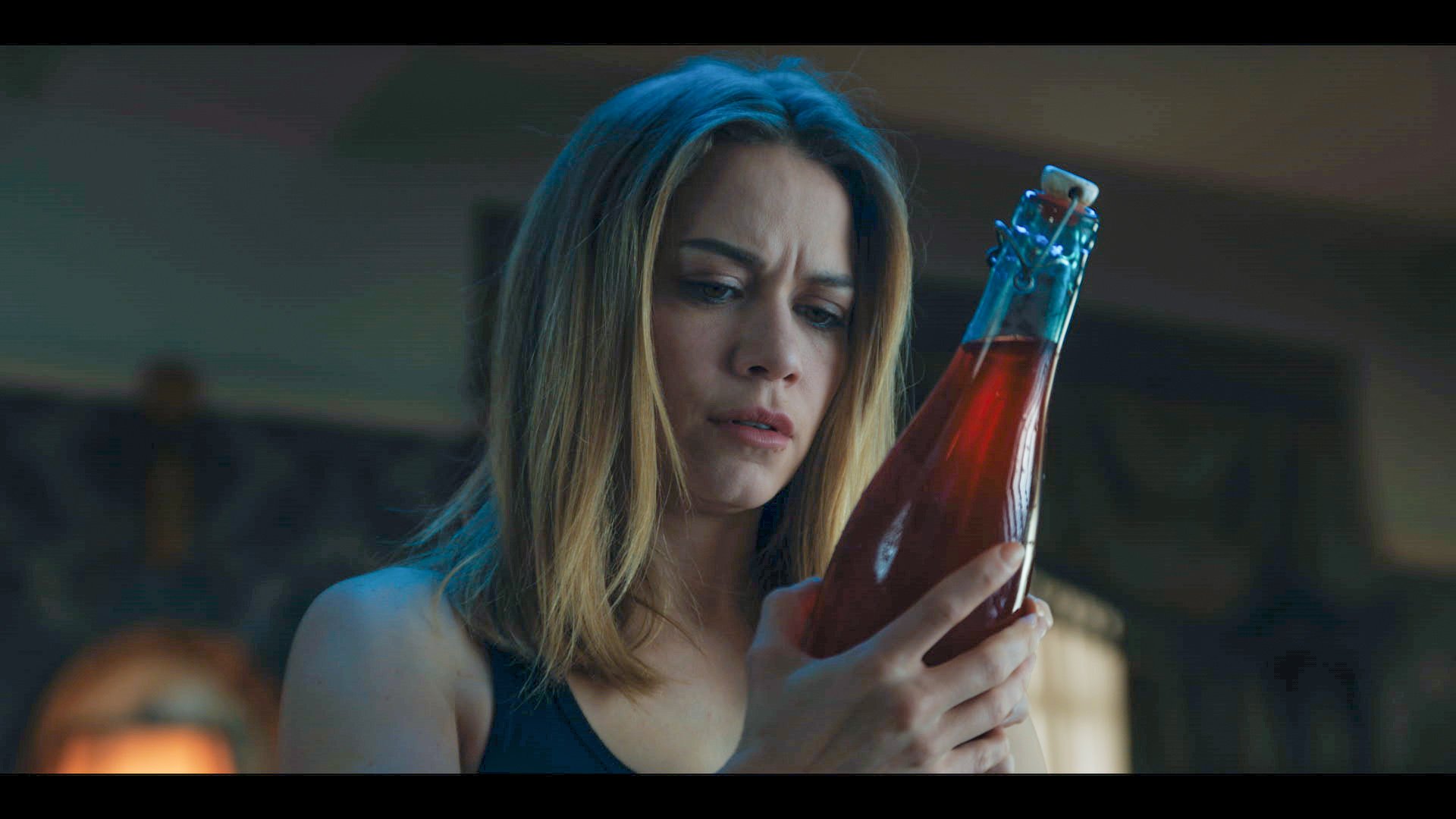 'So Cold the River' star Bethany Joy Lenz stares into an antique bottle of red liquid.