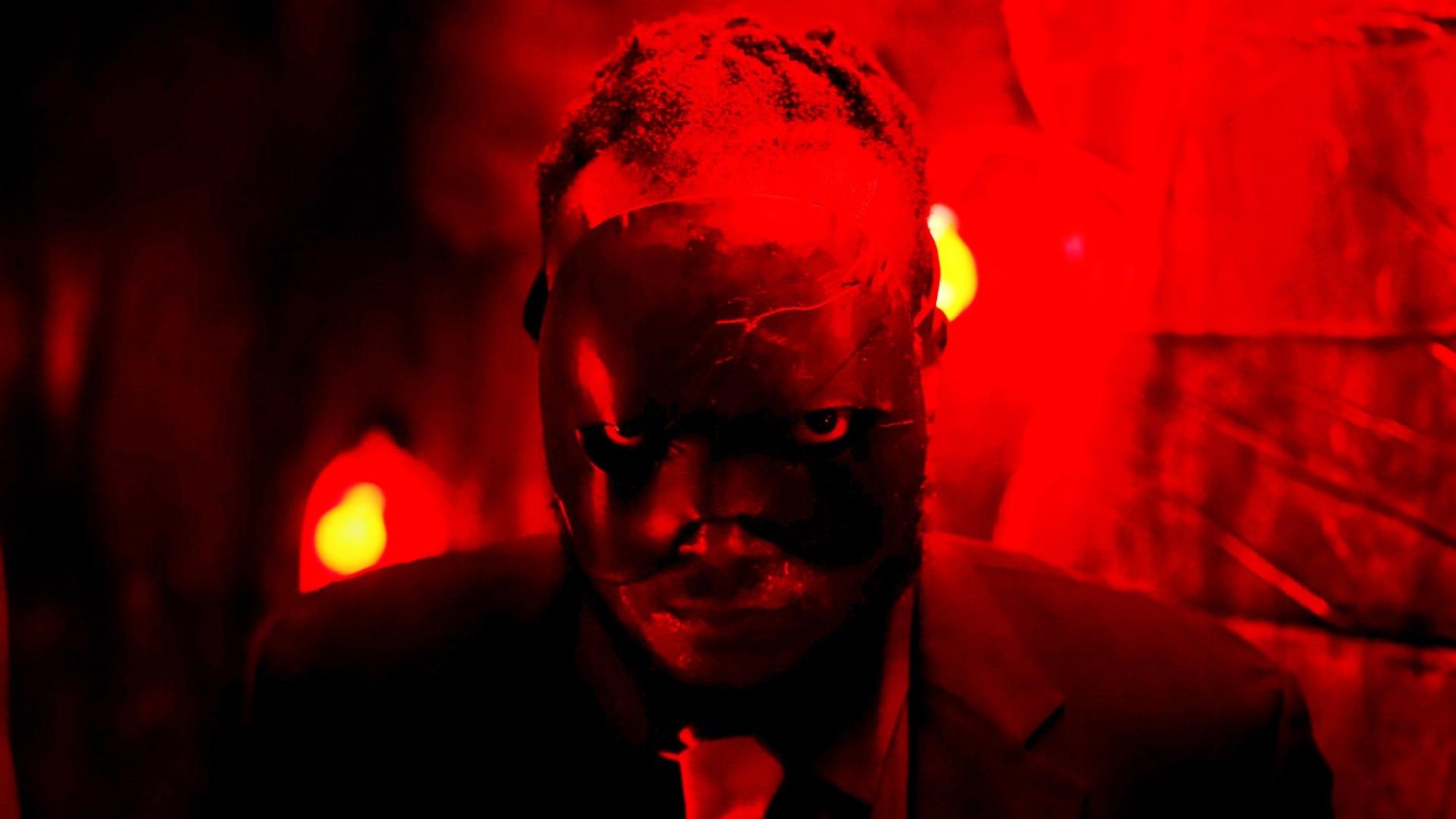 'Bitch Ass' Tunde Laleye as Bitch Ass wearing a black mask looking at the camera