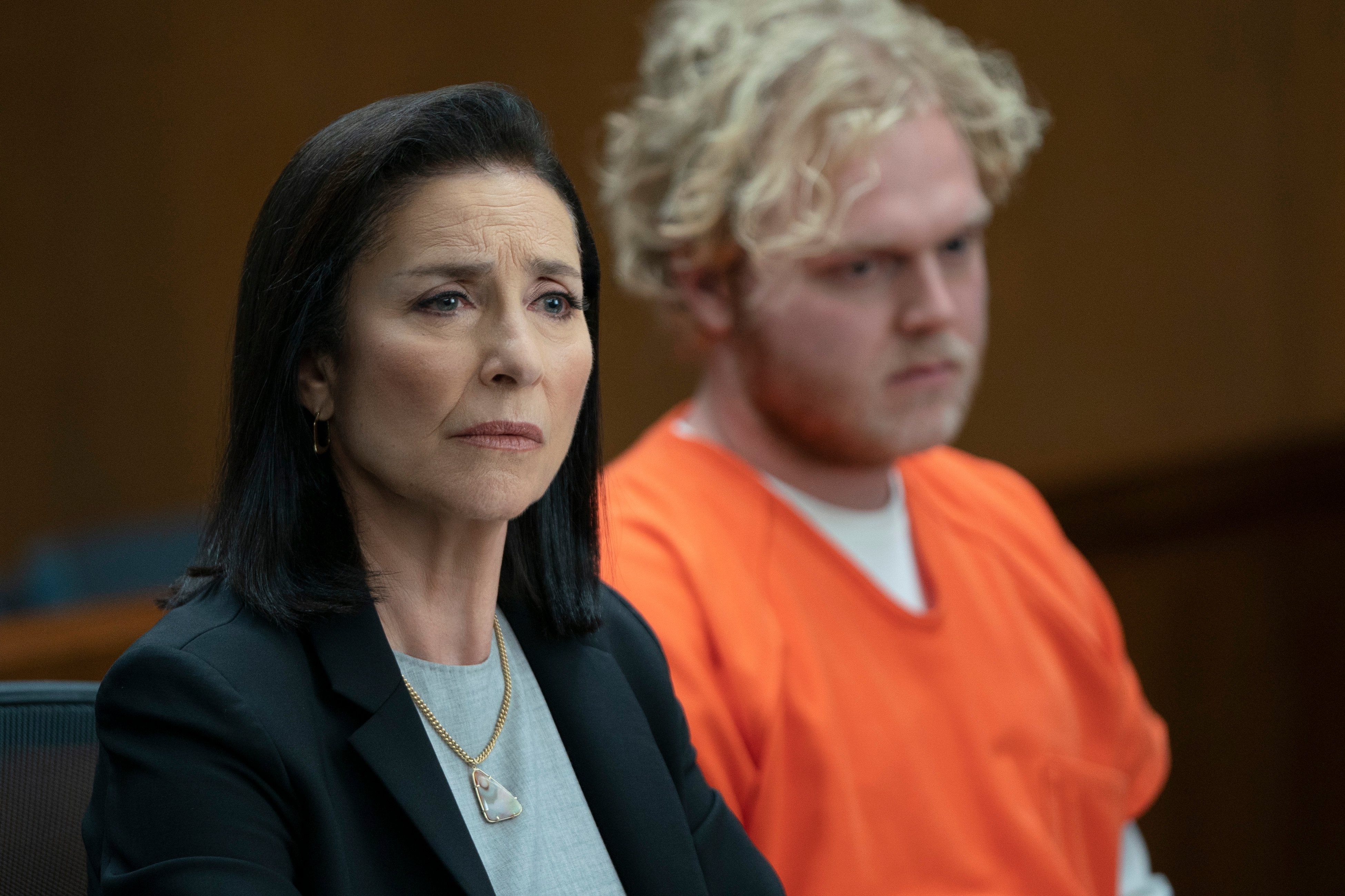 Mimi Rogers as Honey Chandler sitting in front a blond man in an orange jumpsuit in a scene from 'Bosch: Legacy' 