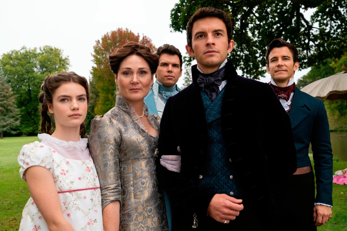 The Bridgerton family, including actor Jonathan Bailey, in episode 207. Violet holds Anthony's arm and stands between him and Hyacinth. Colin and Benedict stand in the background.