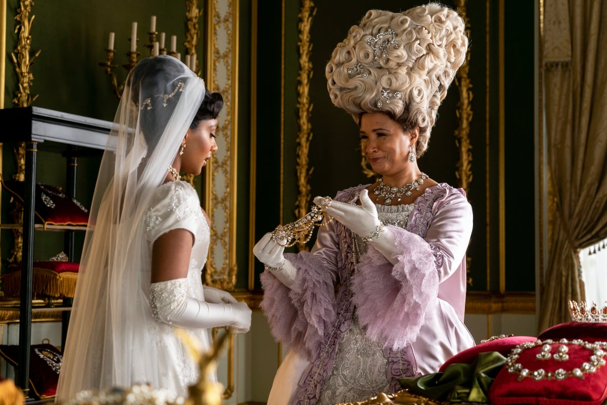 Charithra Chandran as Edwina Sharma and Golda Rosheuvel as Queen Charlotte in Bridgerton Season 2. The Queen shows Edwina a piece of jewelry.  