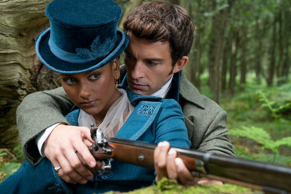 Kate, holding a rifle and in a blue hat, with Anthony in 'Bridgerton' Season 2
