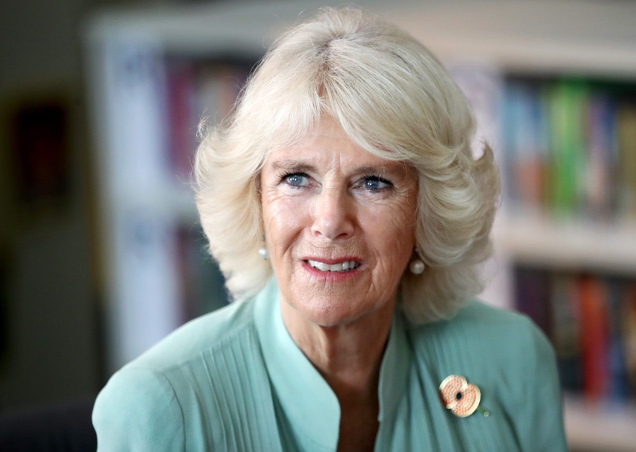 Camilla Parker Bowles looking on while wearing a teal outfit