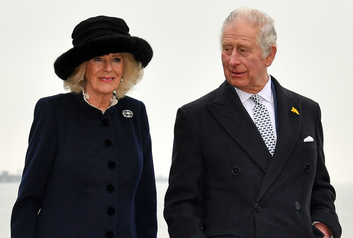 Prince Charles wears a black coat as he looks at Camilla Parker Bowles, who wears a black hat and coat