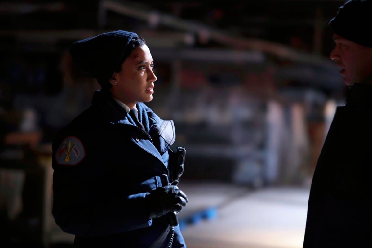 Andy Allo as Seager in Chicago Fire Season 10. Seager wears a coat and hat and appears to be talking to Severide.