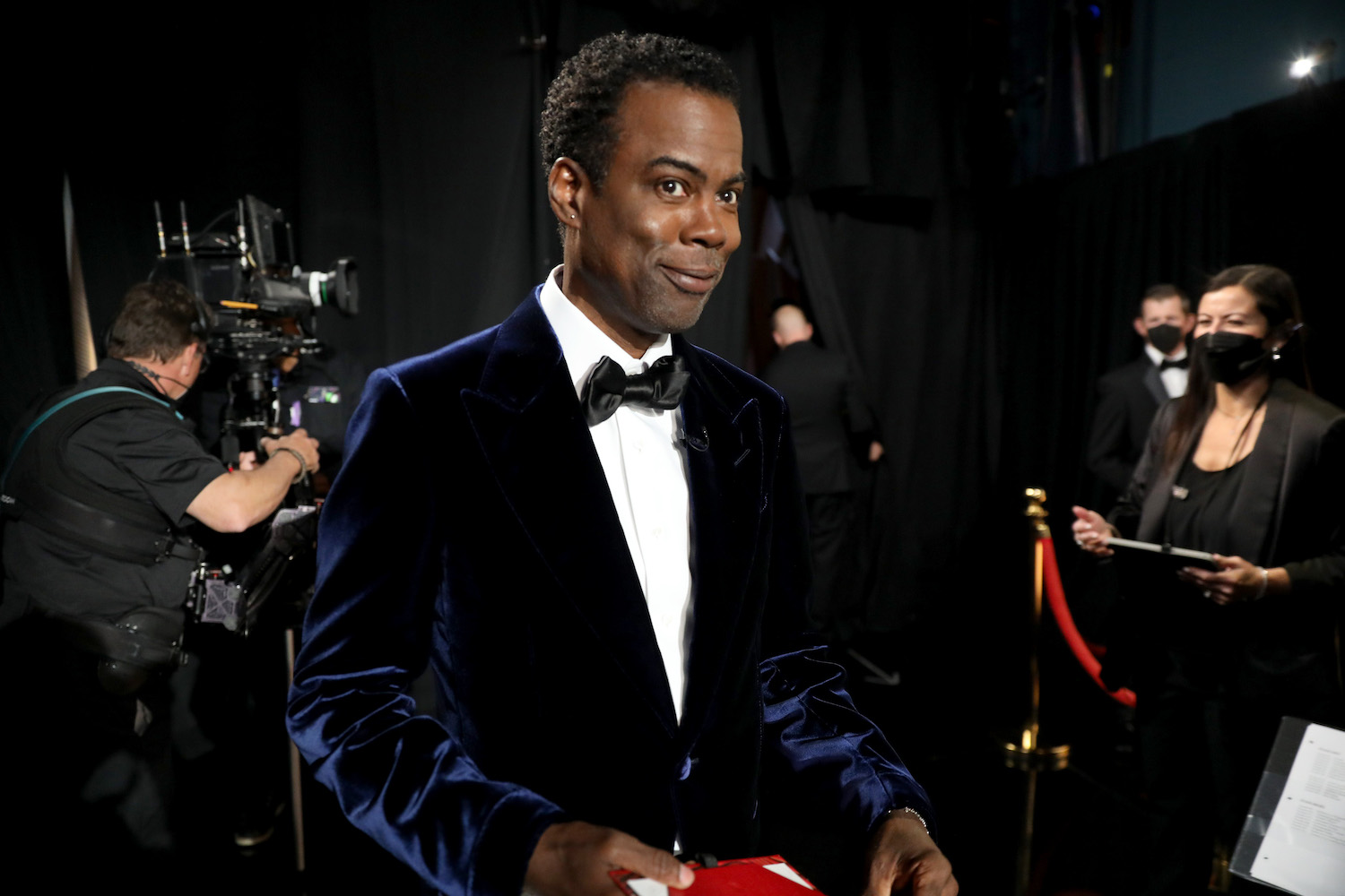 Chris Rock smiling in a suit at the Oscars 2022