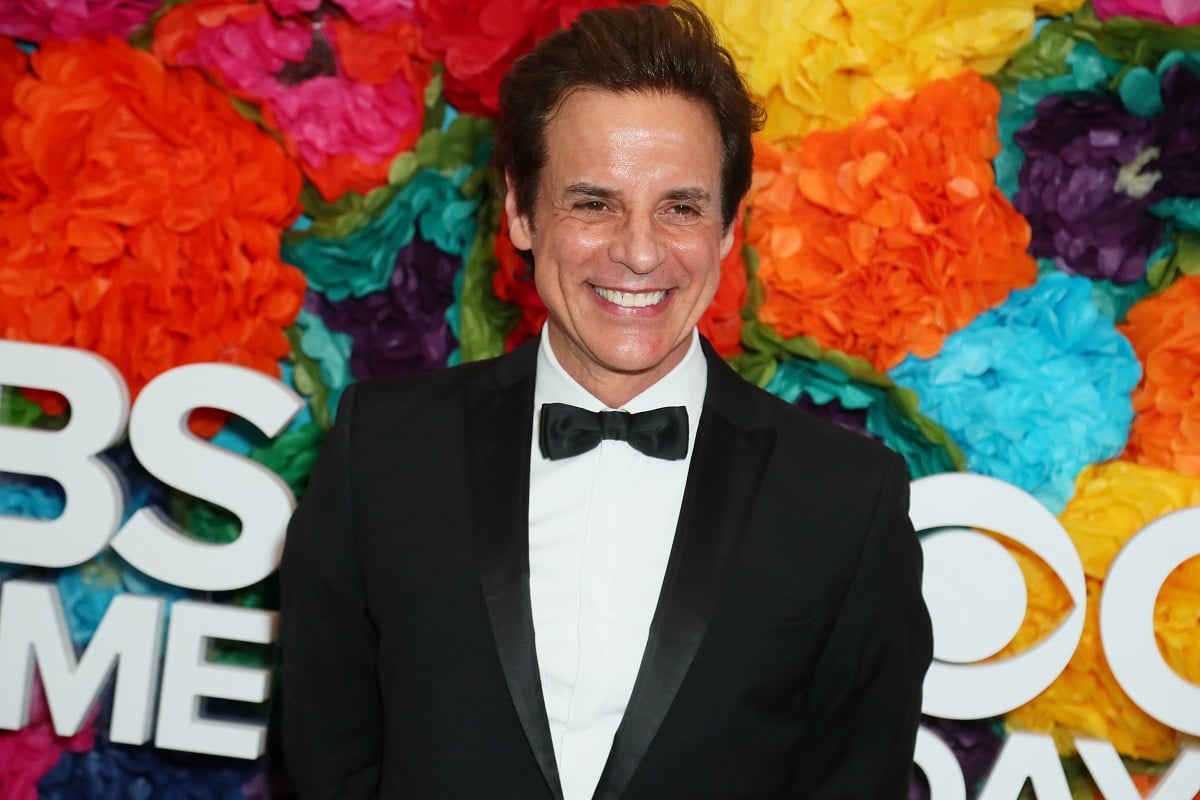 'The Young and the Restless' actor Christian LeBlanc wearing a tuxedo and standing in front of a floral hedge.