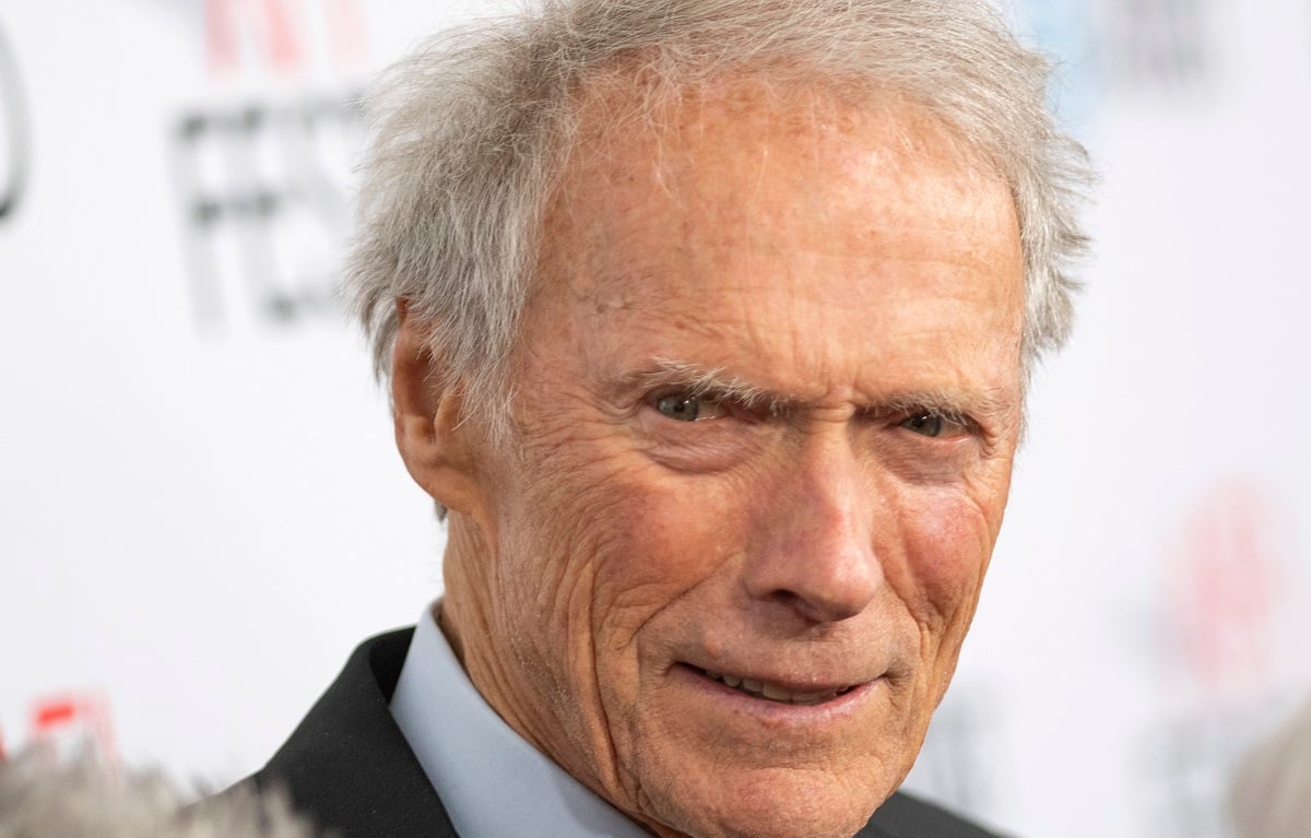 Clint Eastwood sourit en enfilant son costume.