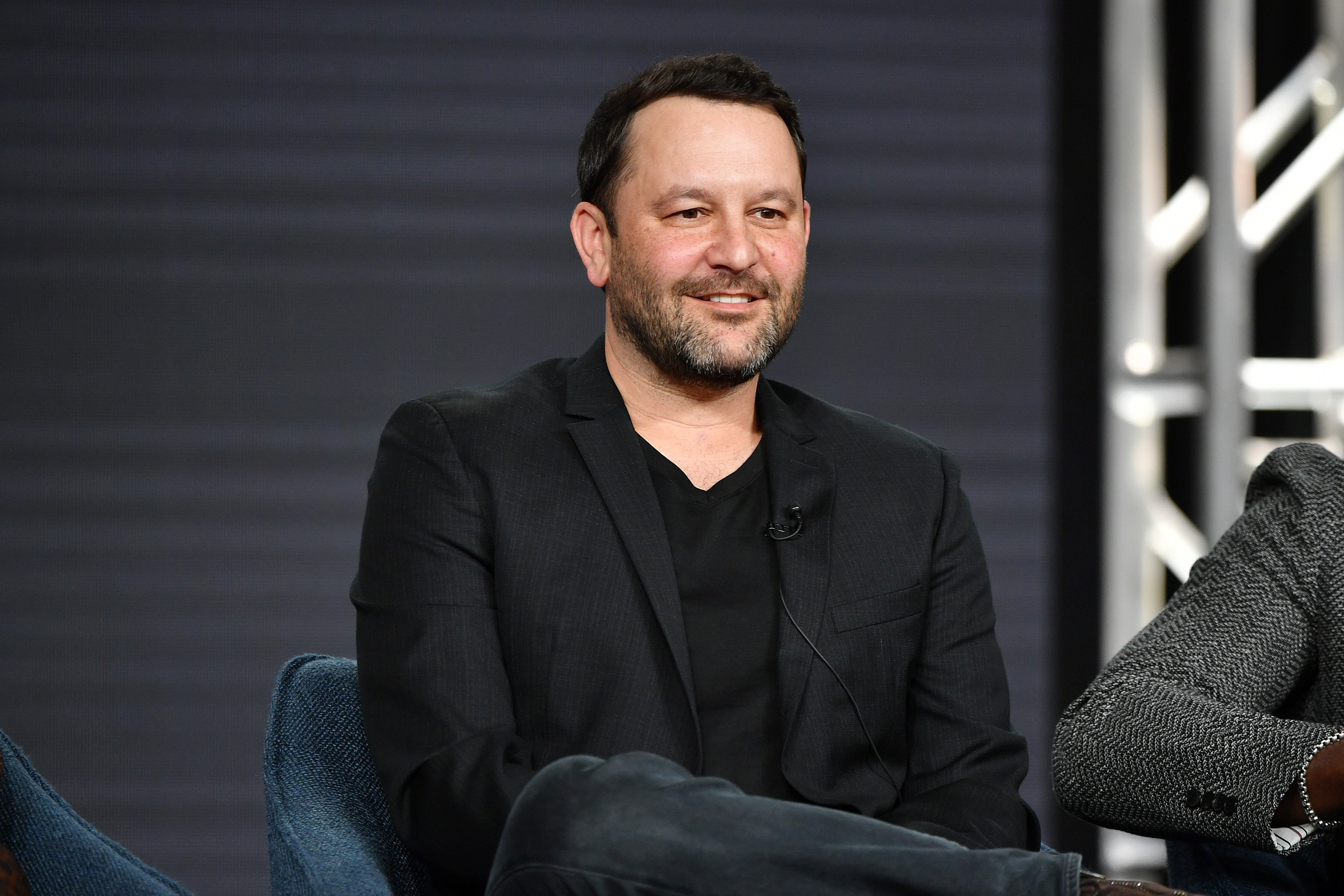 Dan Fogelman, who created 'This Is Us,' which is ending before season 7, wears a black blazer over a black shirt and dark jeans.