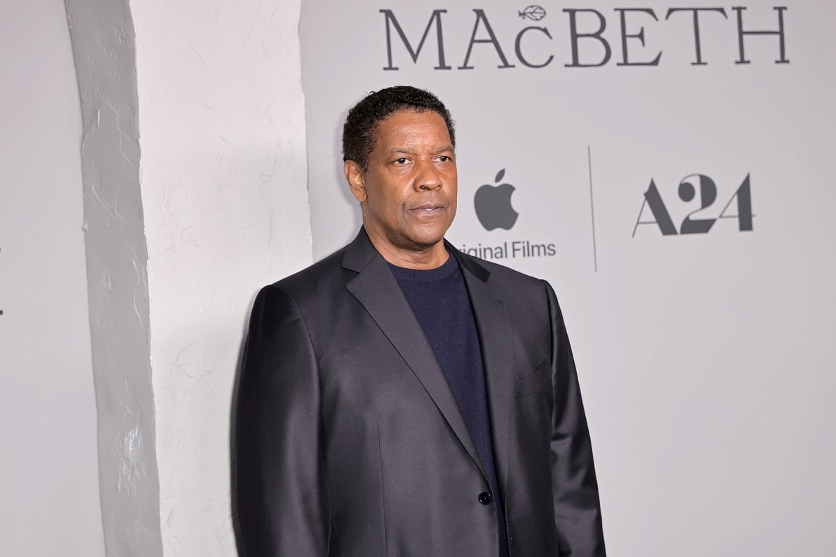 Denzel Washington posing while wearing a black suit.