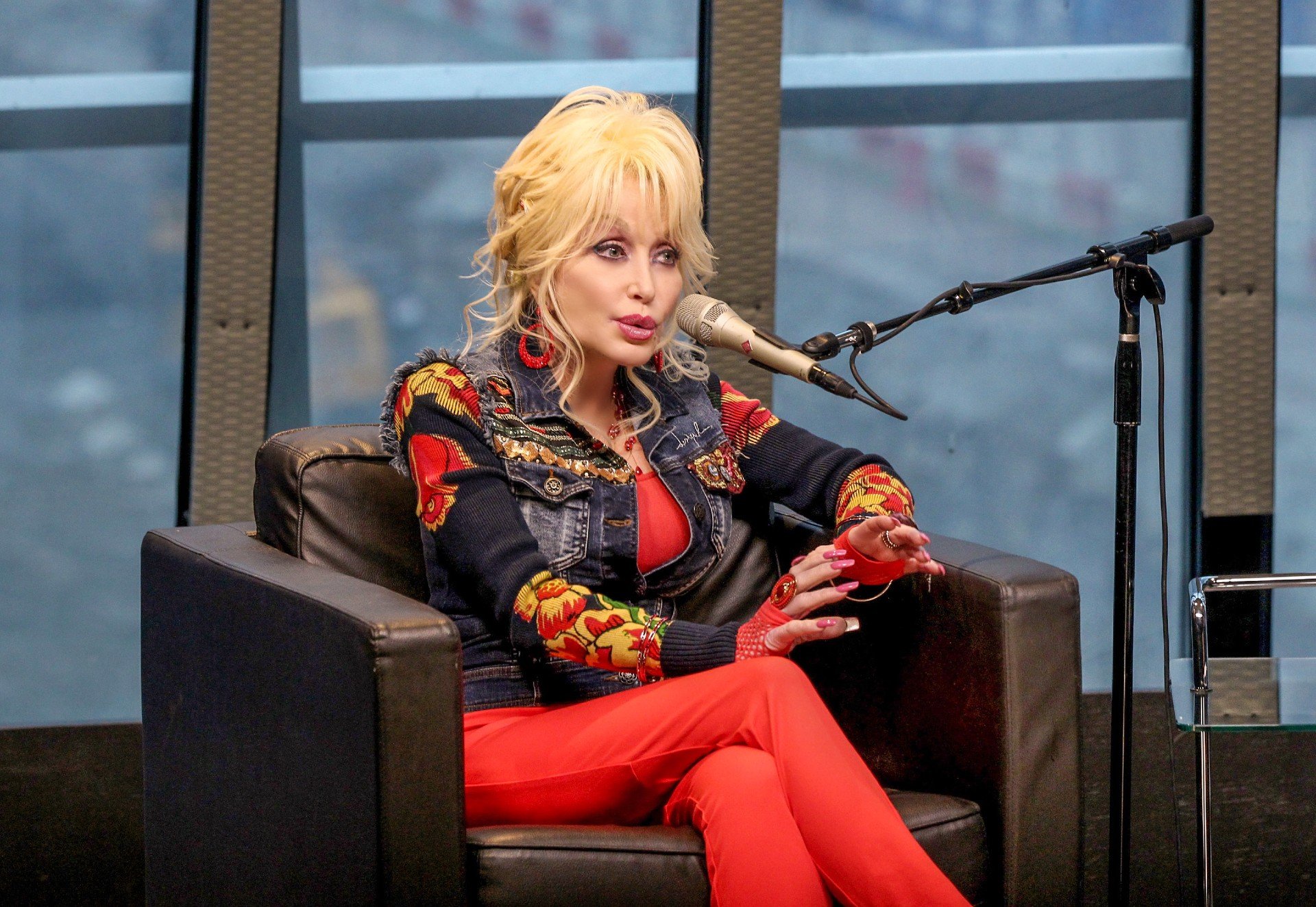 Dolly Parton sits and speaks into a microphone during an interview.