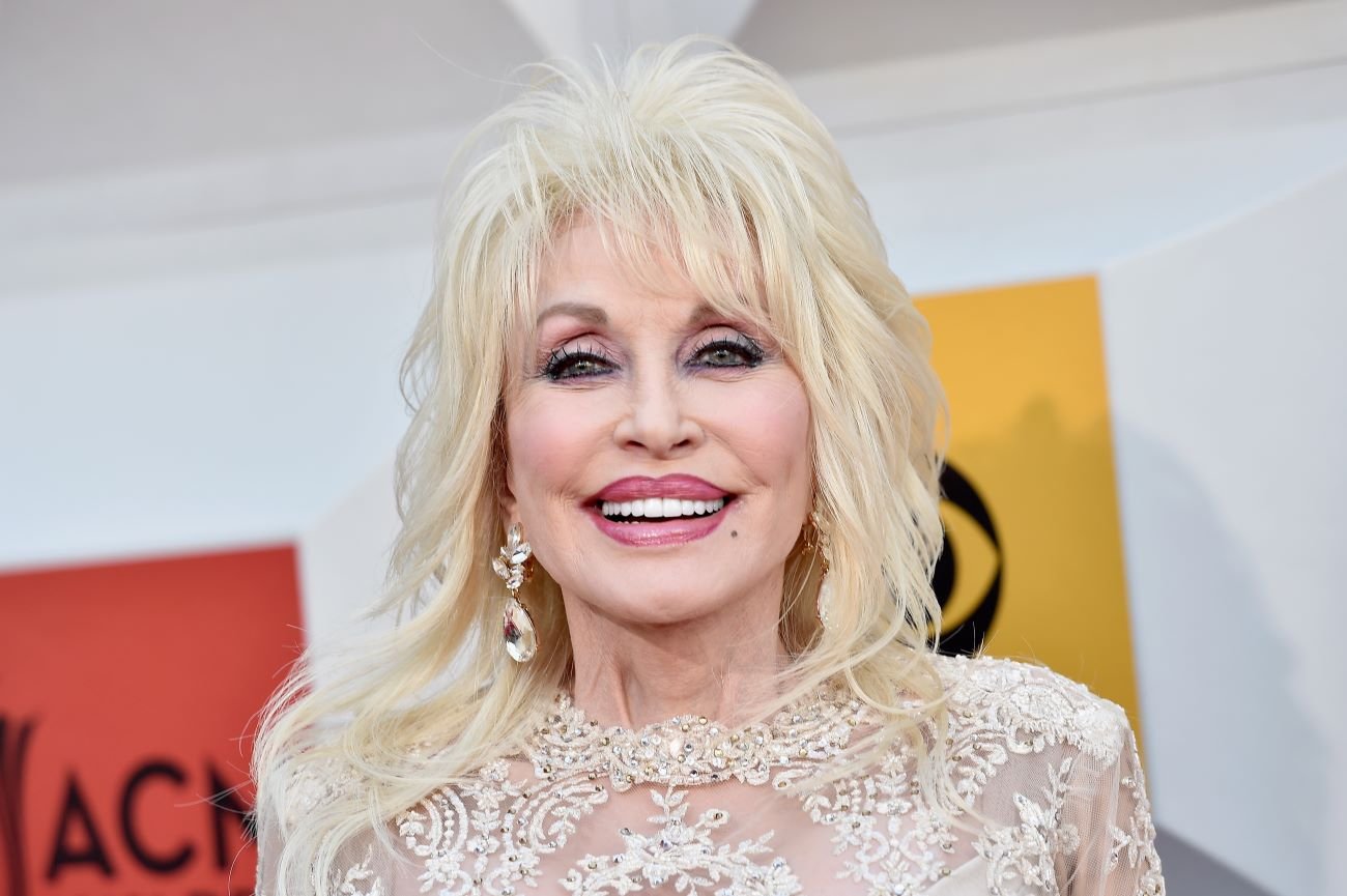 Dolly Parton wears a white lace dress and crystal earrings. 