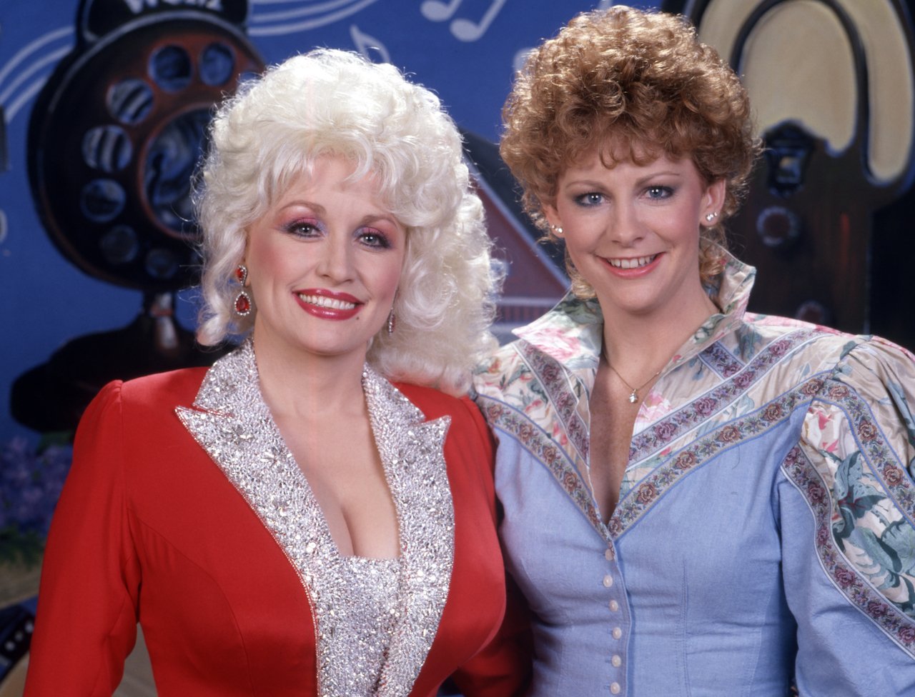 (L-R) Dolly Parton in red and Reba McEntire in blue, c. 1986