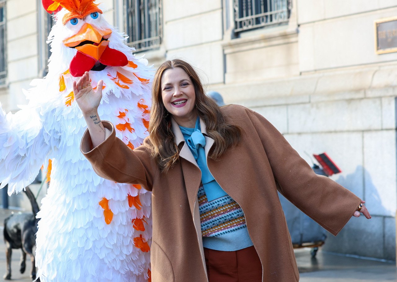 Drew Barrymore with a person in a chicken costume, waving down a taxi together