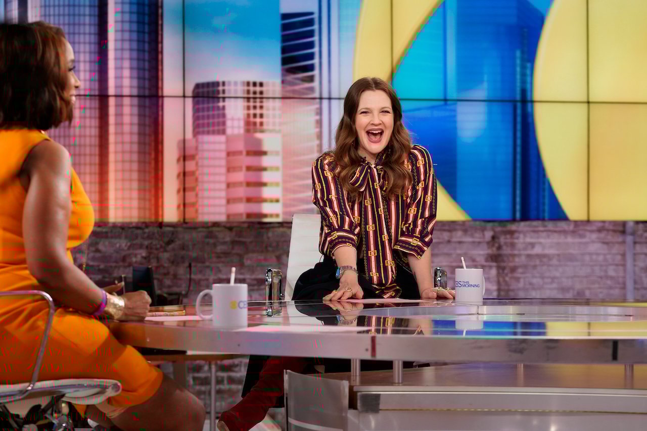 Drew Barrymore seated and dressed in a striped shirt, smiling