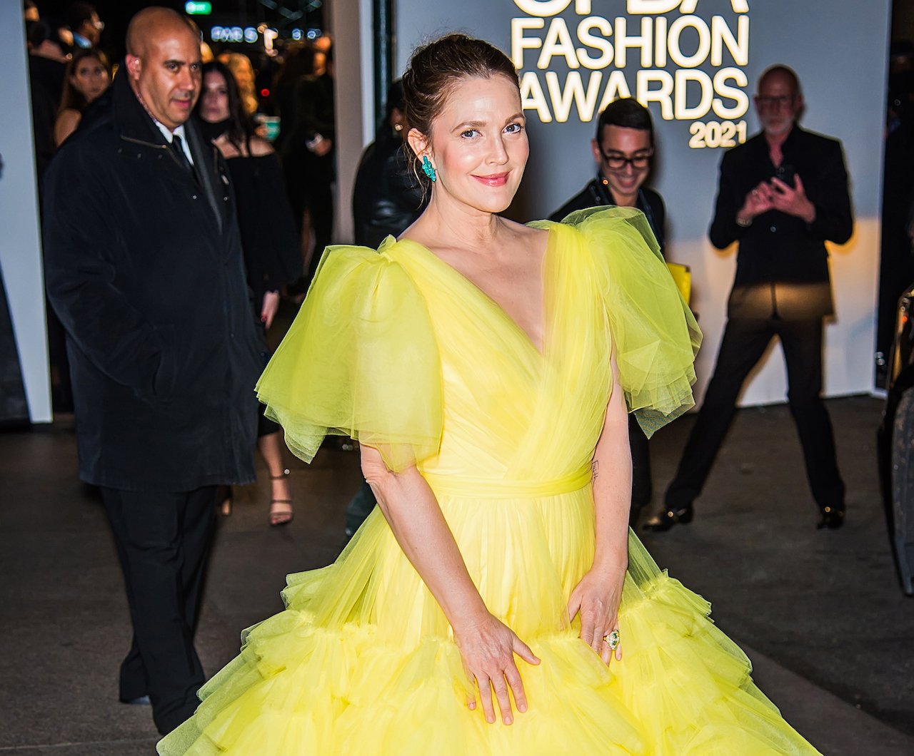 Drew Barrymore poses and smiles in a bright yellow dress