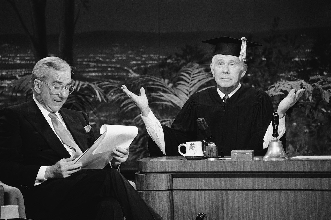 Ed McMahon sits next to Johnny Carson, dressed in a graduation cap and gown, on 'The Tonight Show'