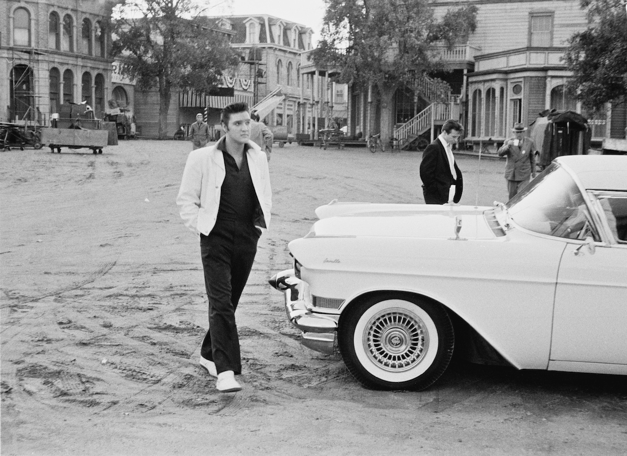 Elvis Presley poses with a Cadillac Eldorado on a movie set