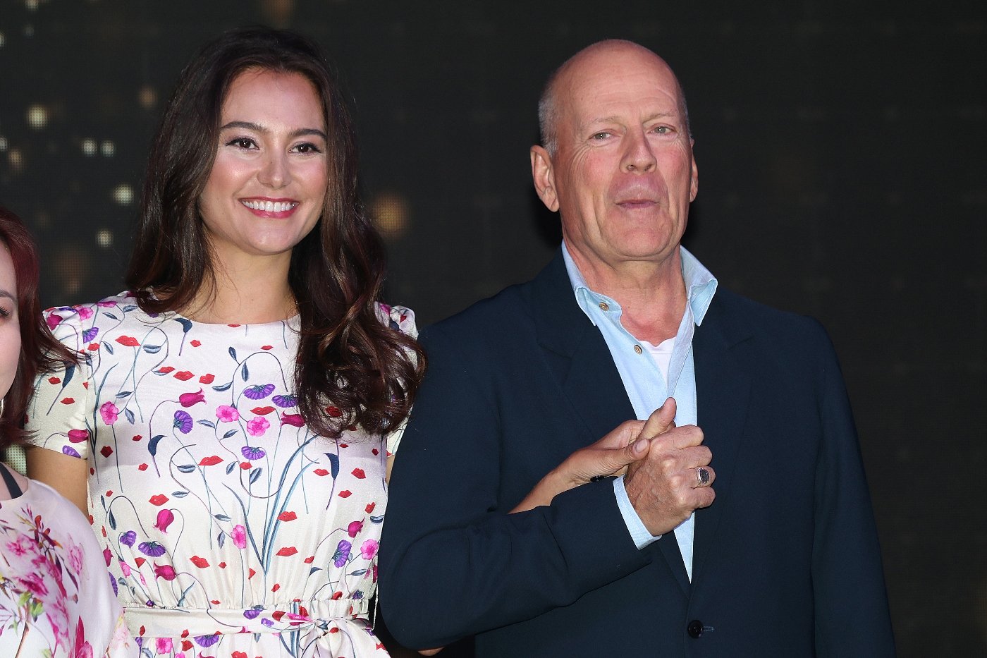 Emma Heming Willis wearing a floral dress holding hands with her husband, Bruce Willis who is wearing a black suit during CocoBaba And Ushopal Activity In Shanghai.