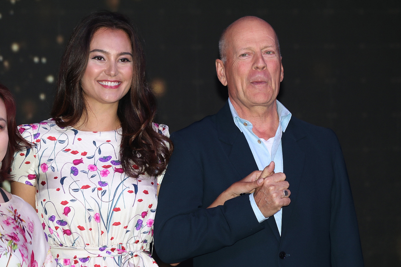 Emma Heming Willis wearing a floral dress holding hands with her husband, Bruce Willis who is wearing a black suit during CocoBaba And Ushopal Activity In Shanghai. 