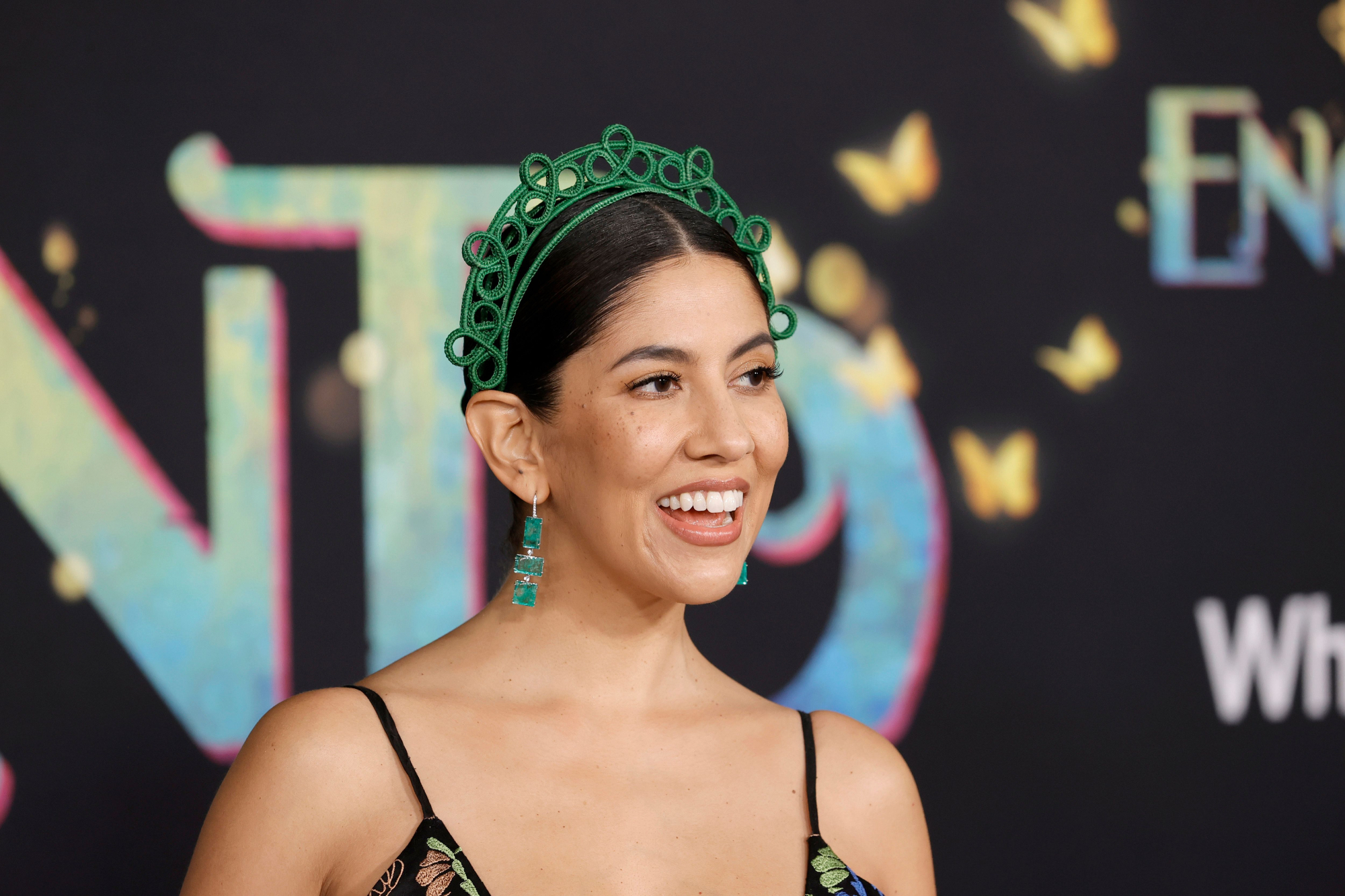 'Encanto' Mirabel voice actor Stephanie Beatriz wearing a green crown in front of the movie step and repeat