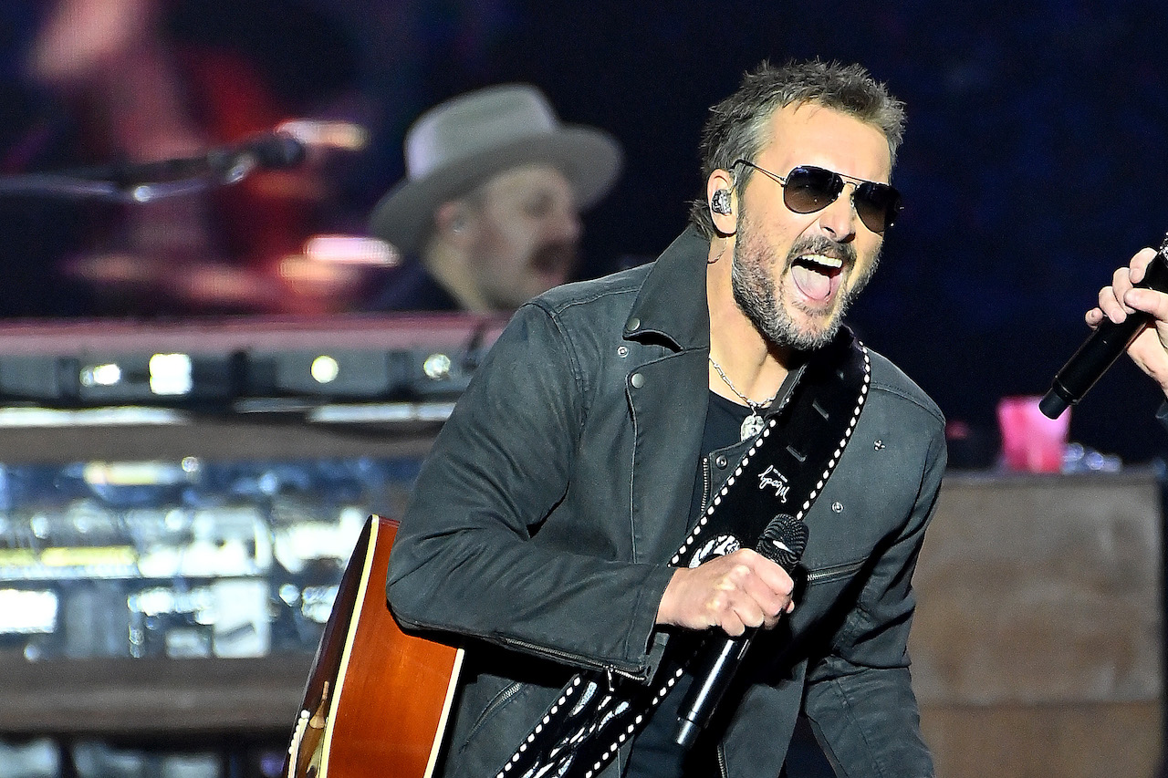 Eric Church in aviator sunglasses, holding a microphone and performing on stage