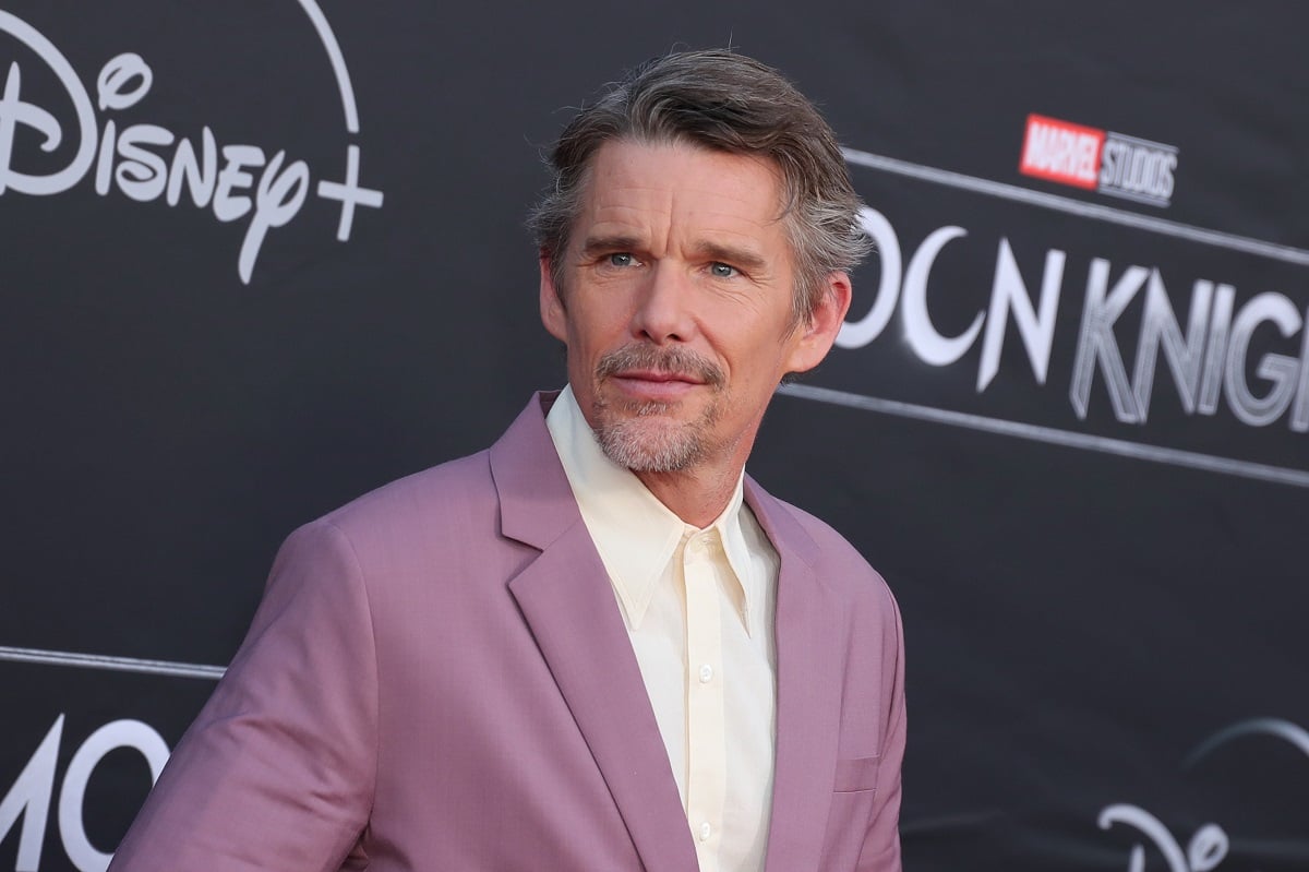 Ethan Hawke smirking while wearing a purple suit.