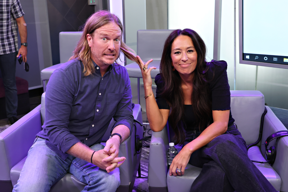 Chip and Joanna Gaines seated in chairs with the ‘Fixer Upper’ star looking scared as his wife pulls at his long hair