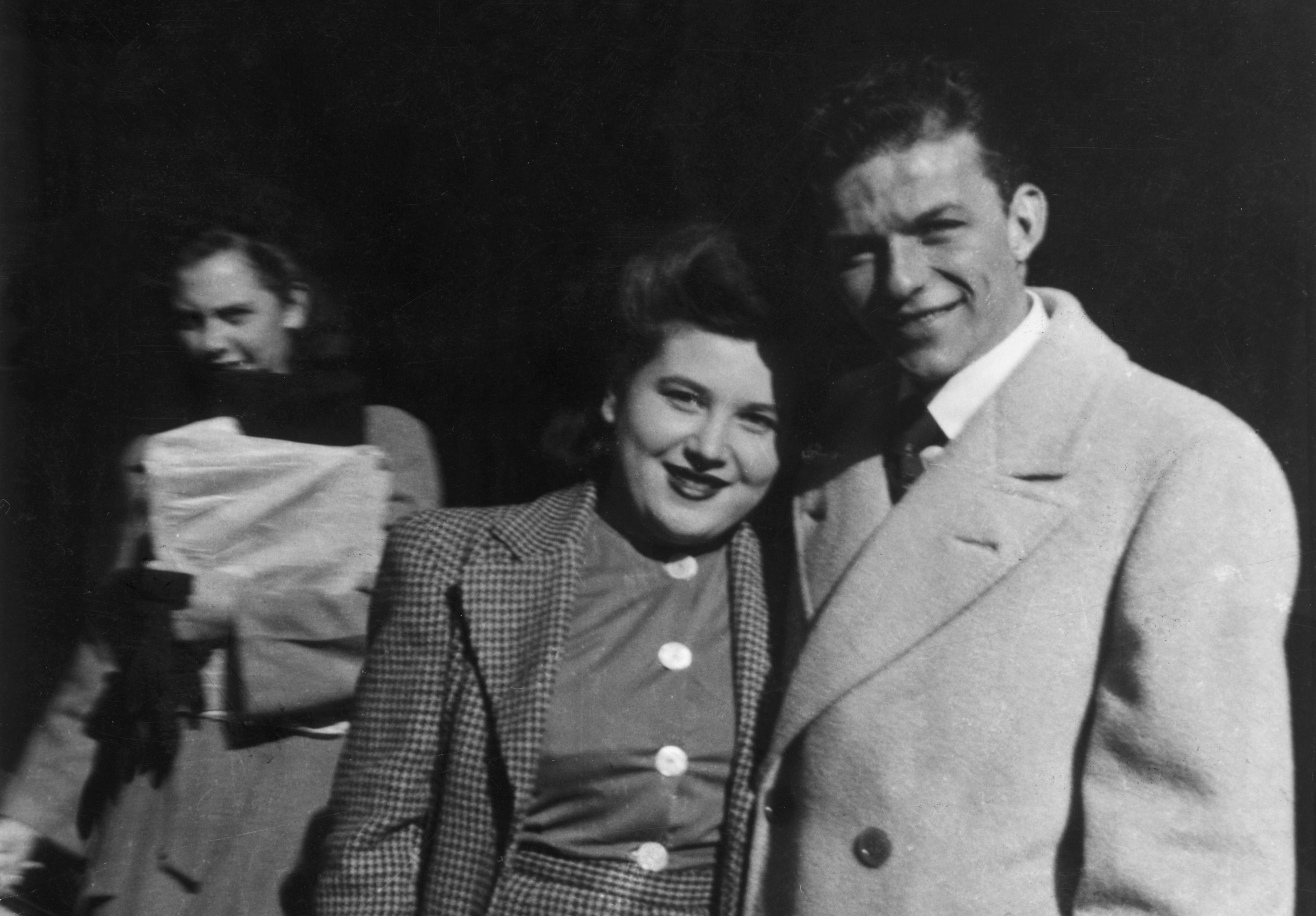 A black and white photo of Dolly Sinatra and Frank Sinatra wearing coats and standing outside.