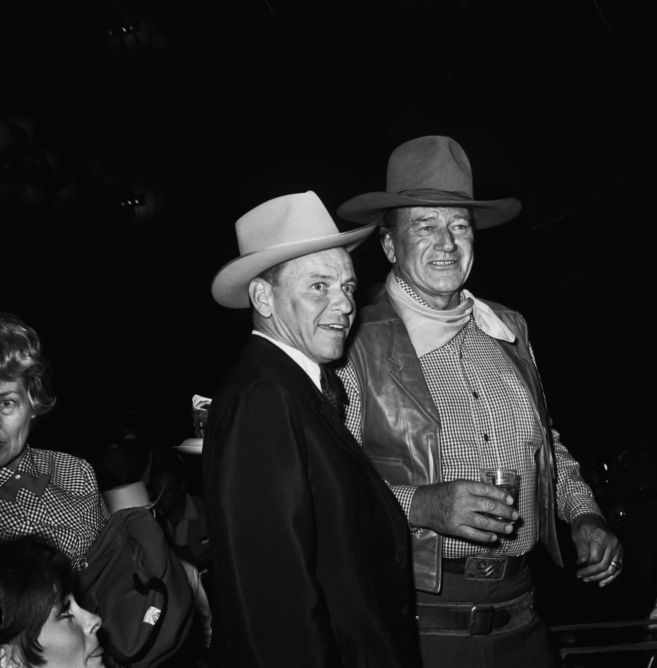 A black and white picture of Frank Sinatra and John Wayne wearing cowboy hats.