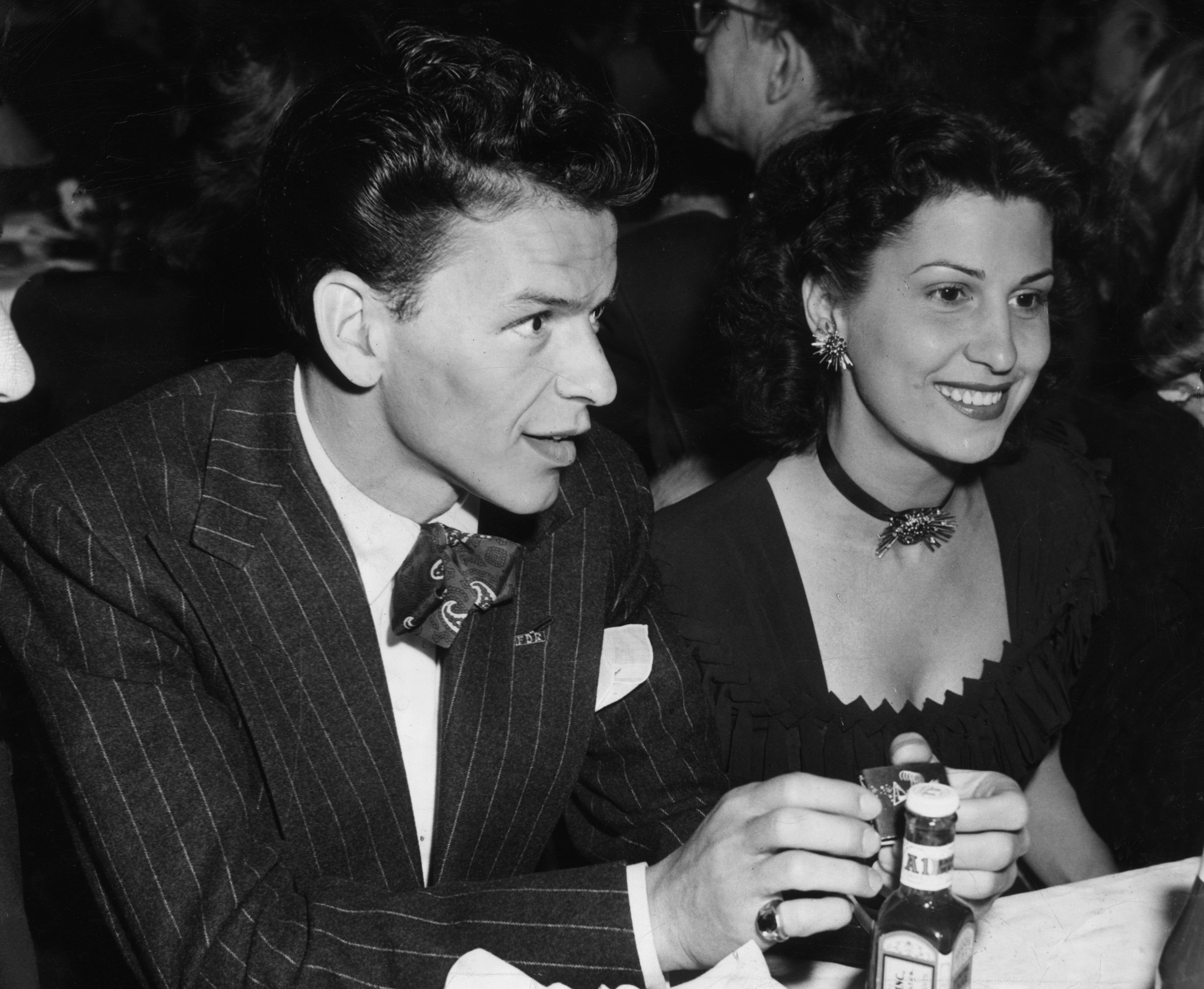 A black and white photo of Frank Sinatra and his former wife Nancy Barbato sitting at a table. 