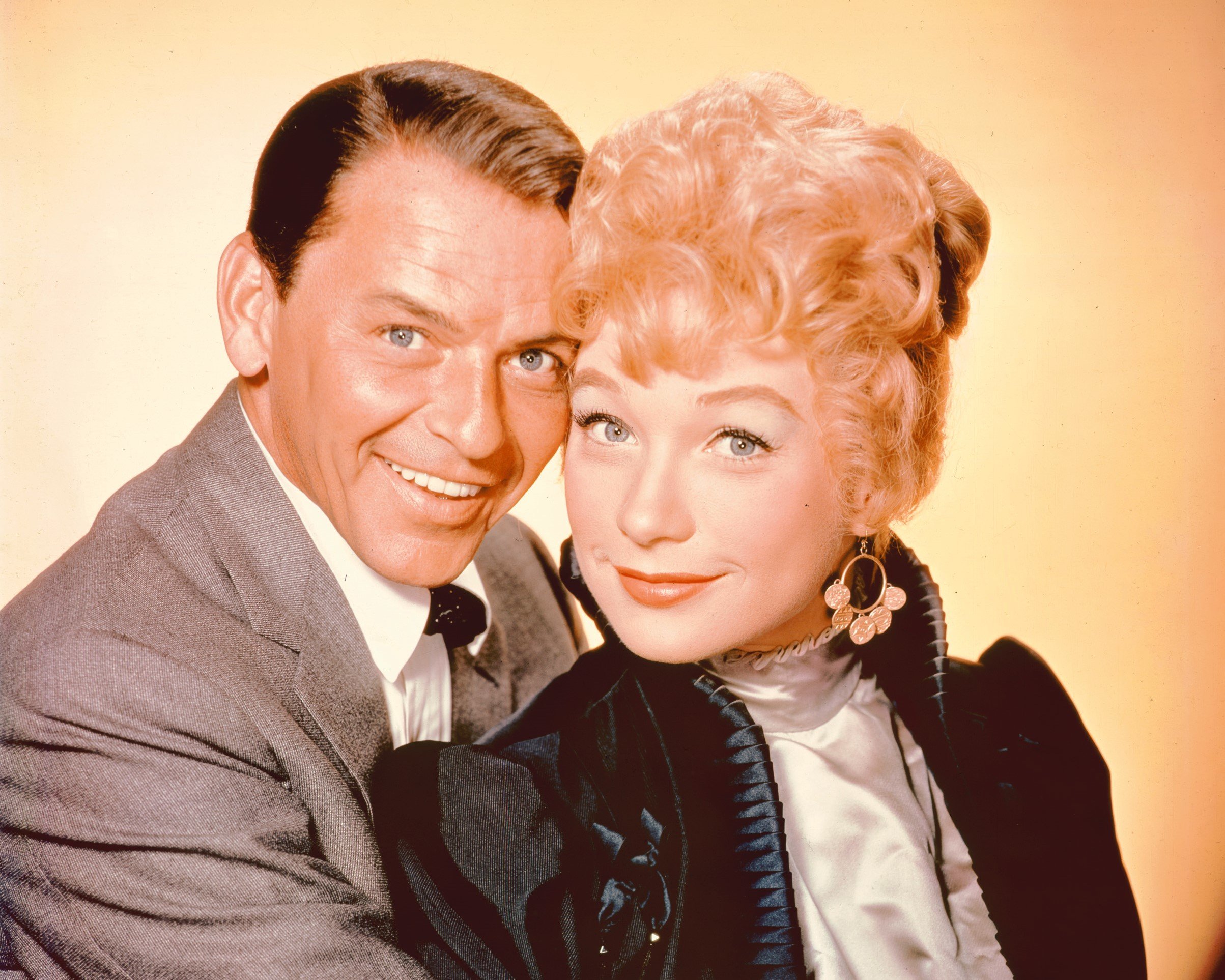 Frank Sinatra and Shirley MacLaine pose together against a yellow background.